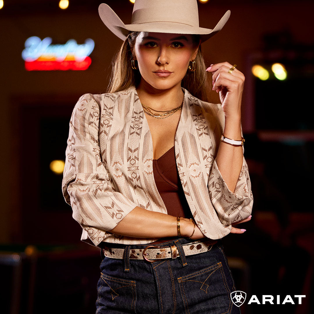 Woman wearing a cowboy hat and patterned blouse with Ariat branding.