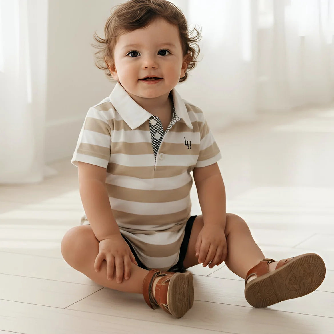 Child wearing a striped polo shirt sitting on a light wooden floor.