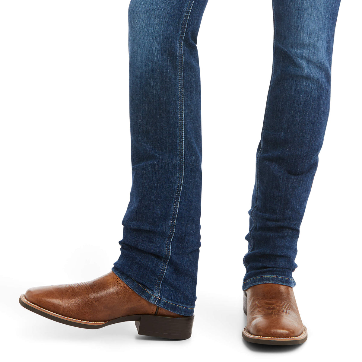 Ariat Women's Abby Perfect Rise Straight Leg Jean. Blue jeans worn by a person with brown leather shoes on a white background