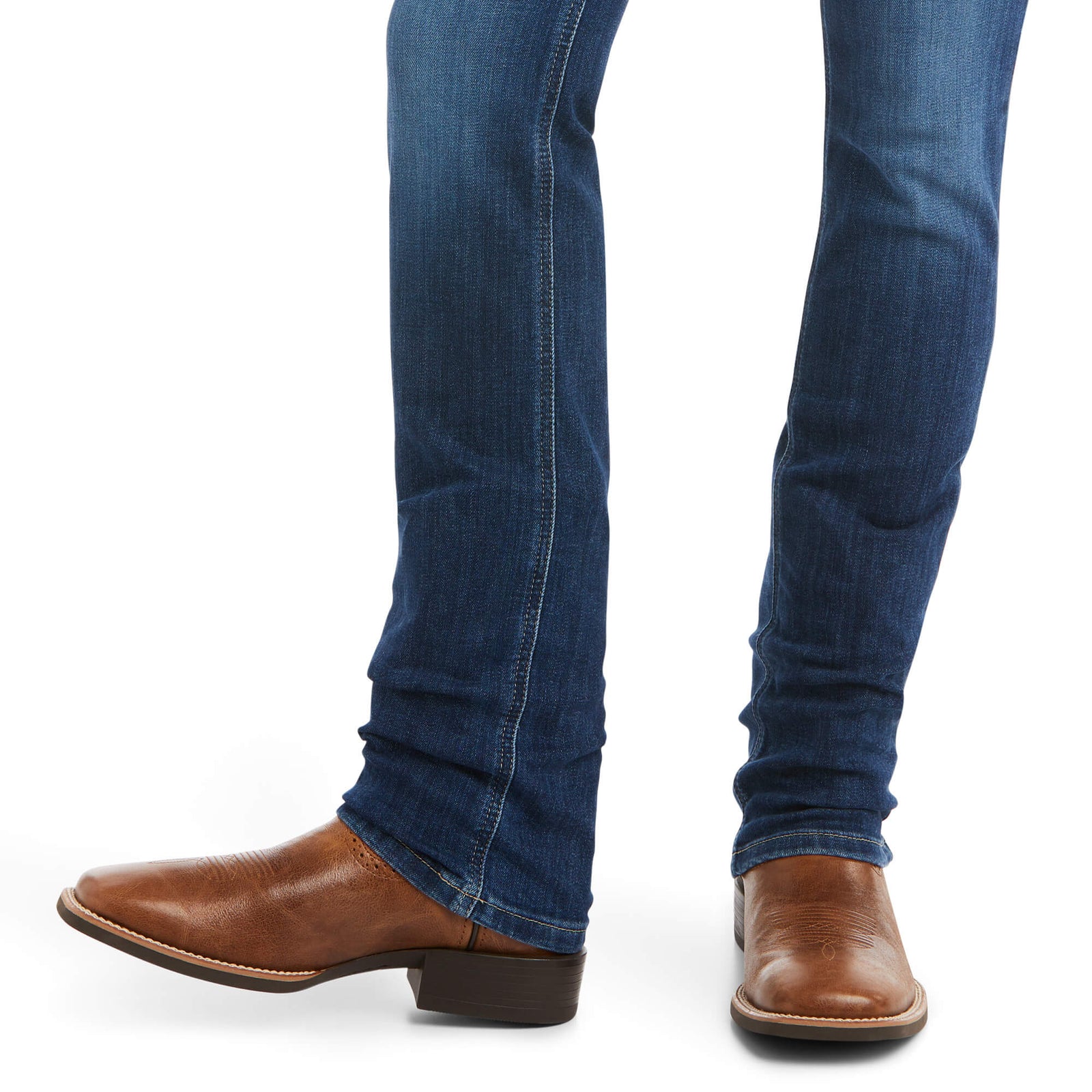 Ariat Women's Abby Perfect Rise Straight Leg Jean. Blue jeans worn by a person with brown leather shoes on a white background