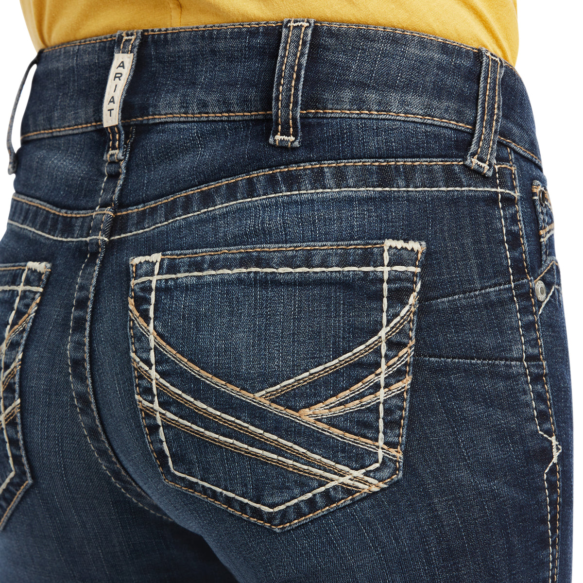Ariat Women's Lexie Perfect Rise Boot Cut Jean. Close-up of blue jeans with a yellow shirt partially visible