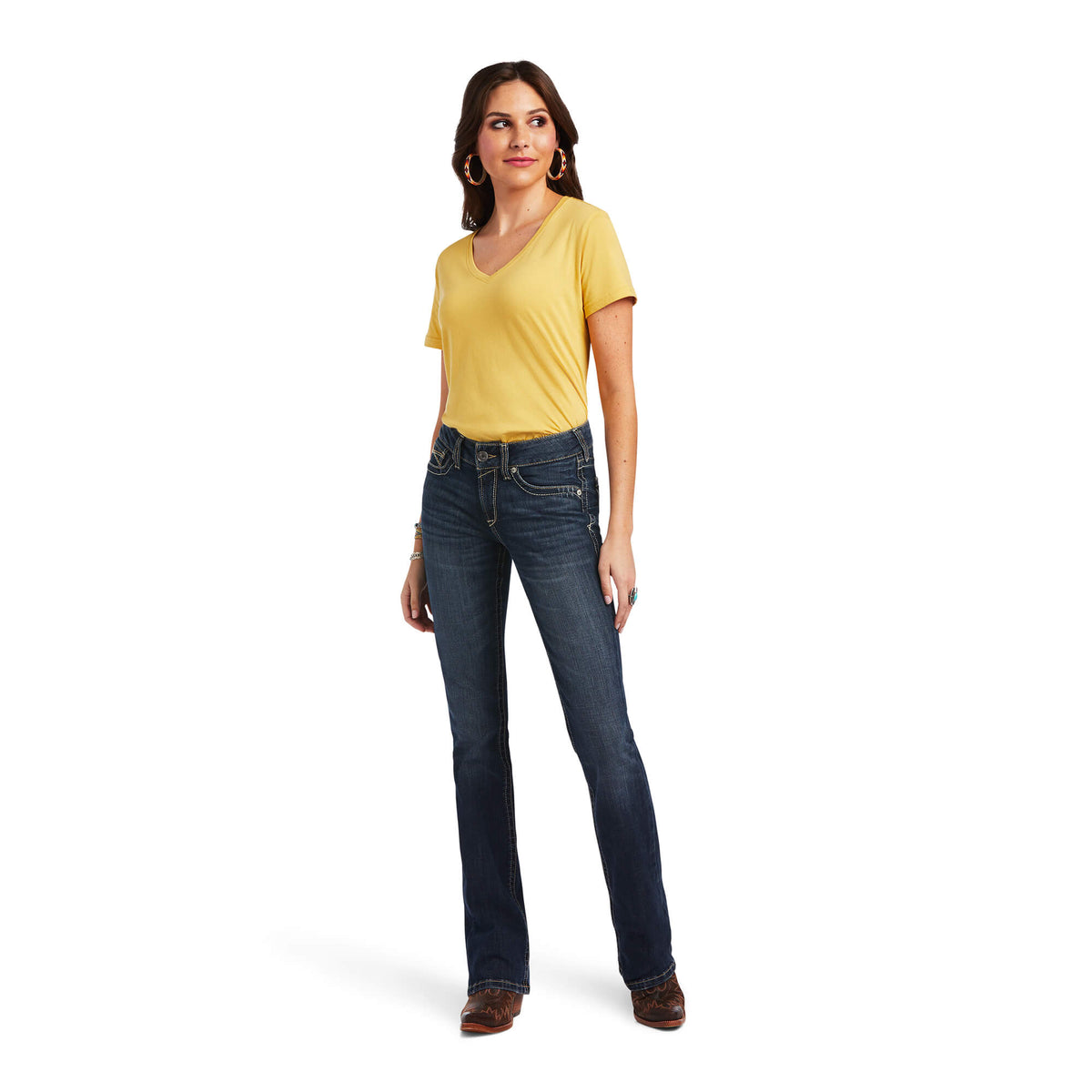 Ariat Women's Lexie Perfect Rise Boot Cut Jean. Woman wearing a yellow t-shirt and blue jeans on a white background