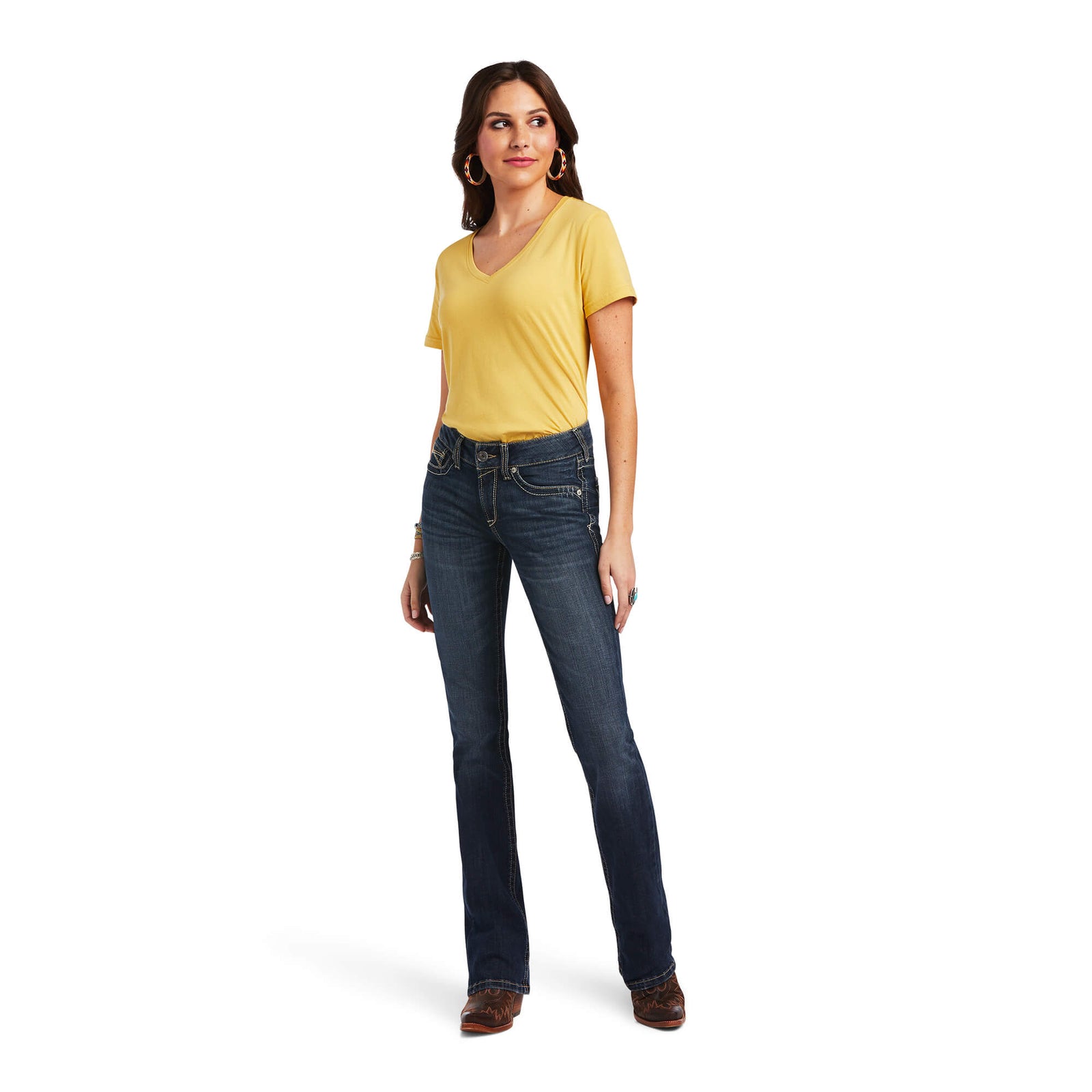 Ariat Women's Lexie Perfect Rise Boot Cut Jean. Woman wearing a yellow t-shirt and blue jeans on a white background