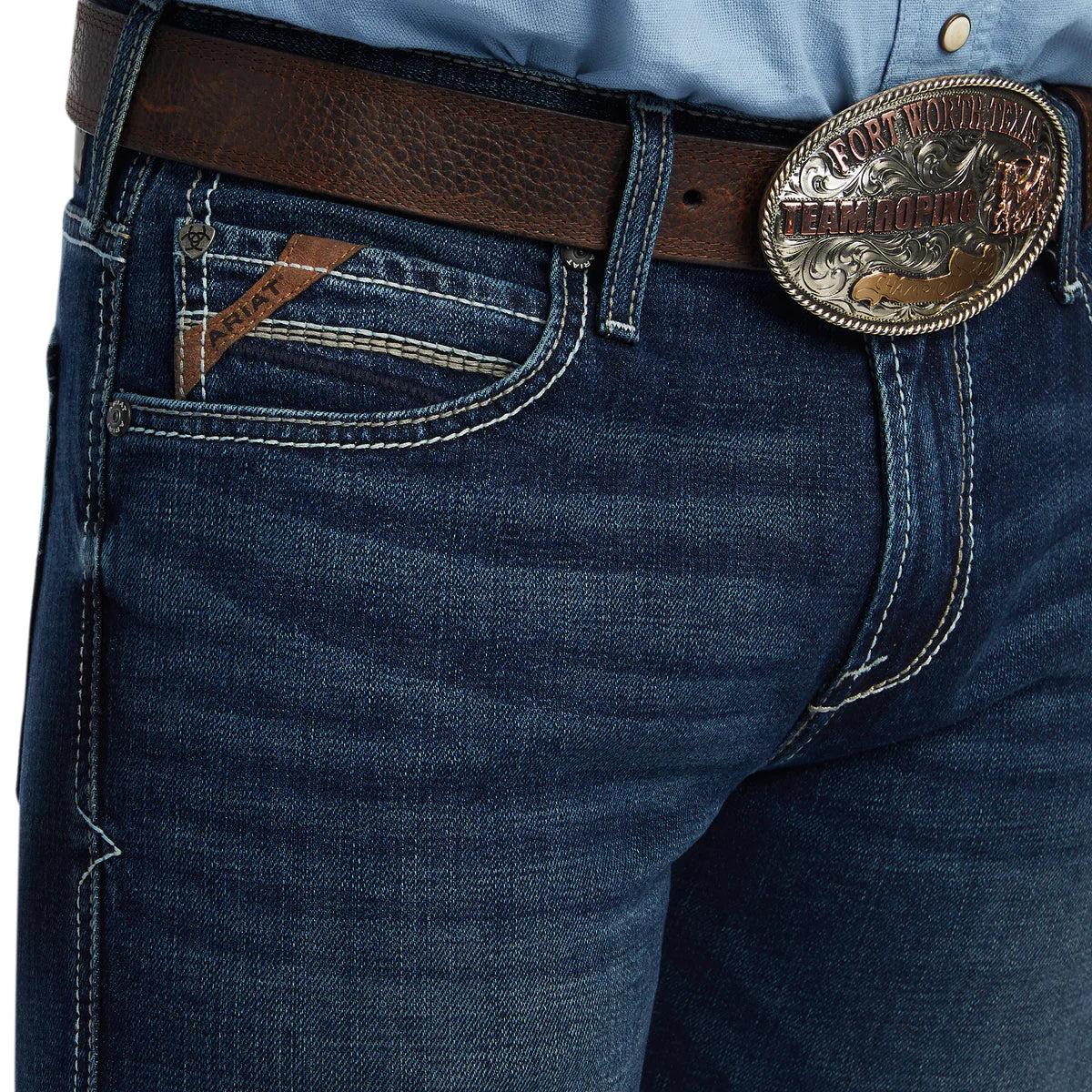 Close-up of blue jeans with a brown belt and decorative buckle.