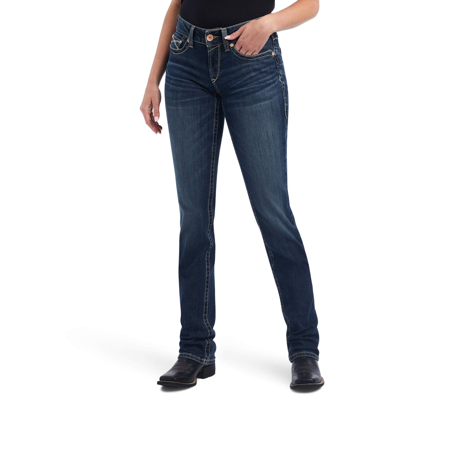 Ariat Women's Freesia Straight Leg Jean. A woman standing and facing the front, wearing mid-rise straight leg blue jeans and black boots.