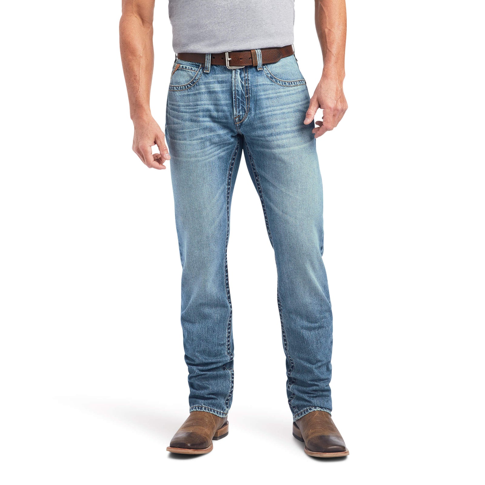A man wearing Ariat Men's M4 Madera Relaxed Fit Jean, standing with one hand in pocket and looking to the side.