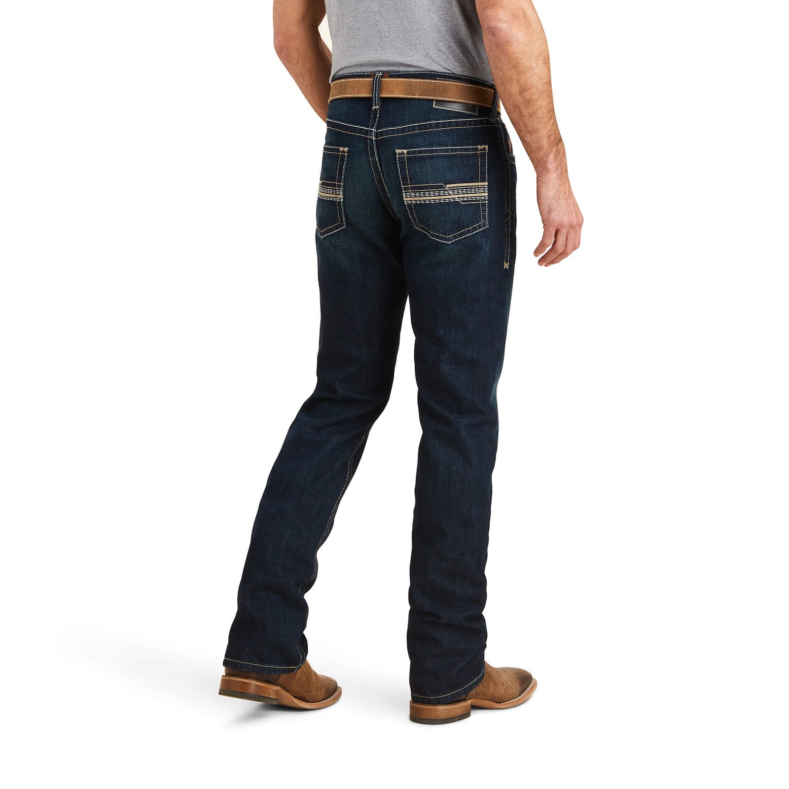 A man wearing Ariat Men's M5 Winifield Straight Leg Jeans with a belt and shoes, standing against a white background.
