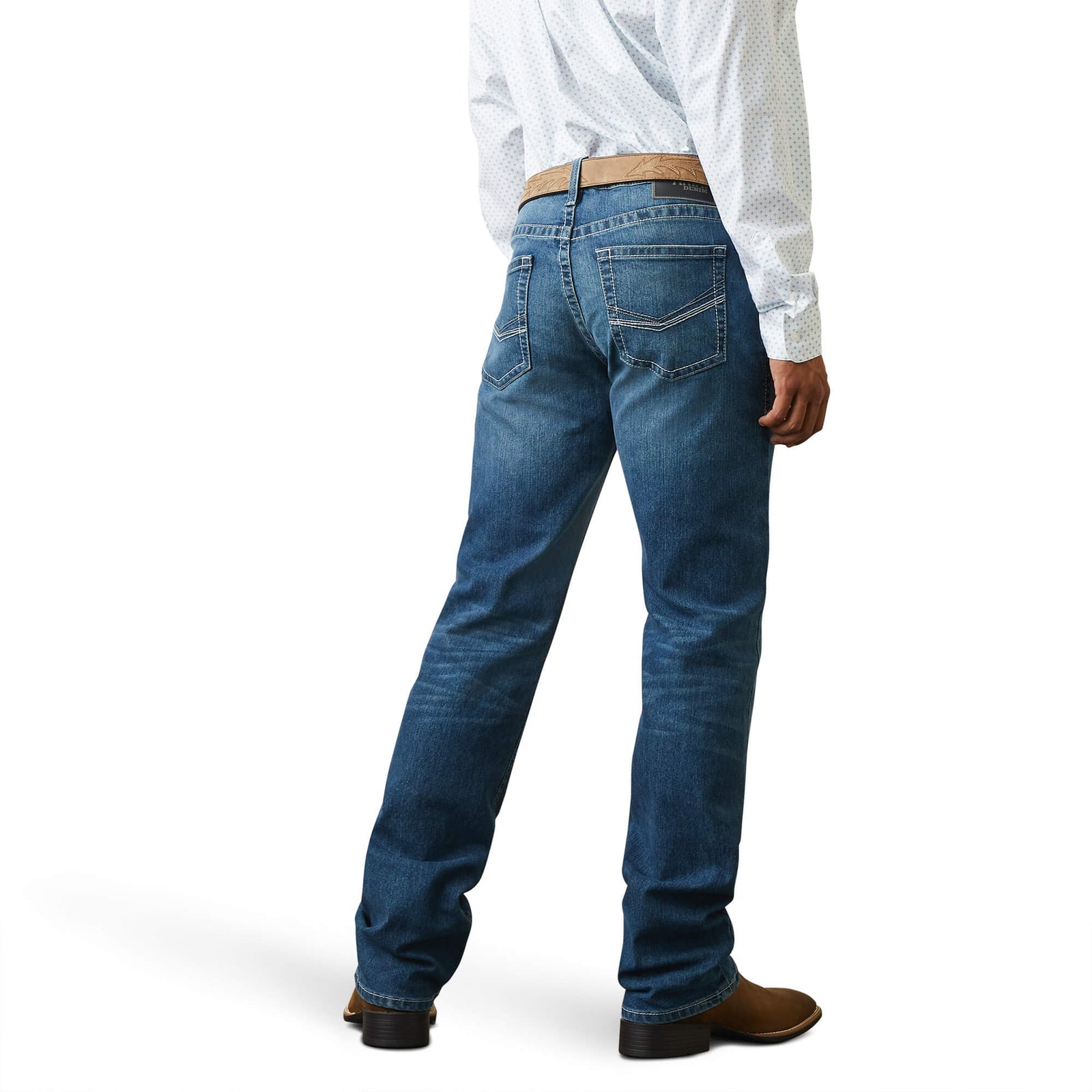 A man standing straight, wearing a white shirt and Ariat Men's M5 Devon Straight Leg Jeans with brown boots and a brown belt.