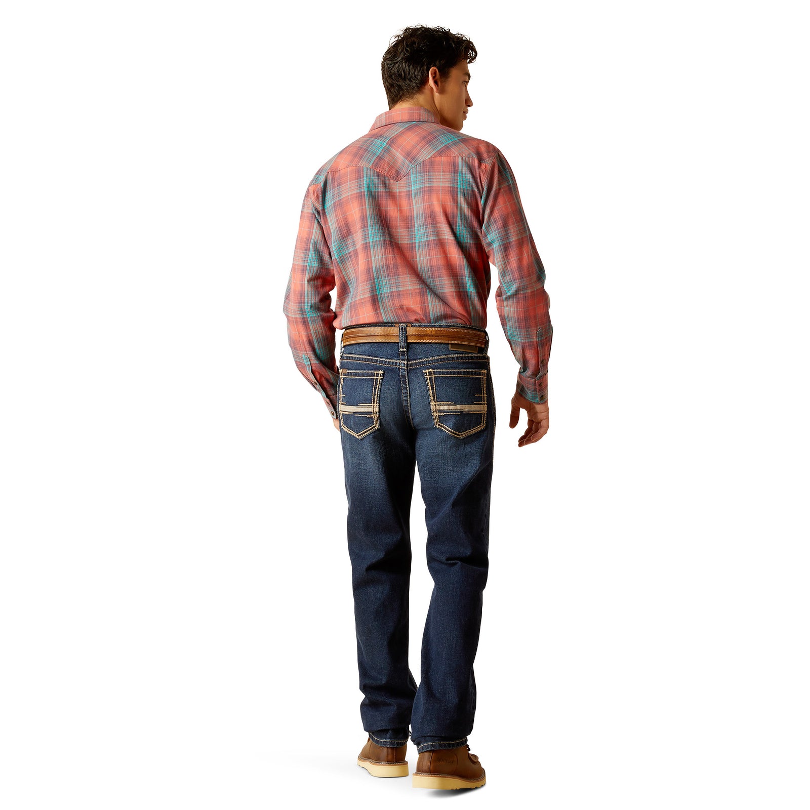 A man standing wearing Ariat Men's M8 Ranger Straight Leg Jeans with a plaid shirt and leather boots.