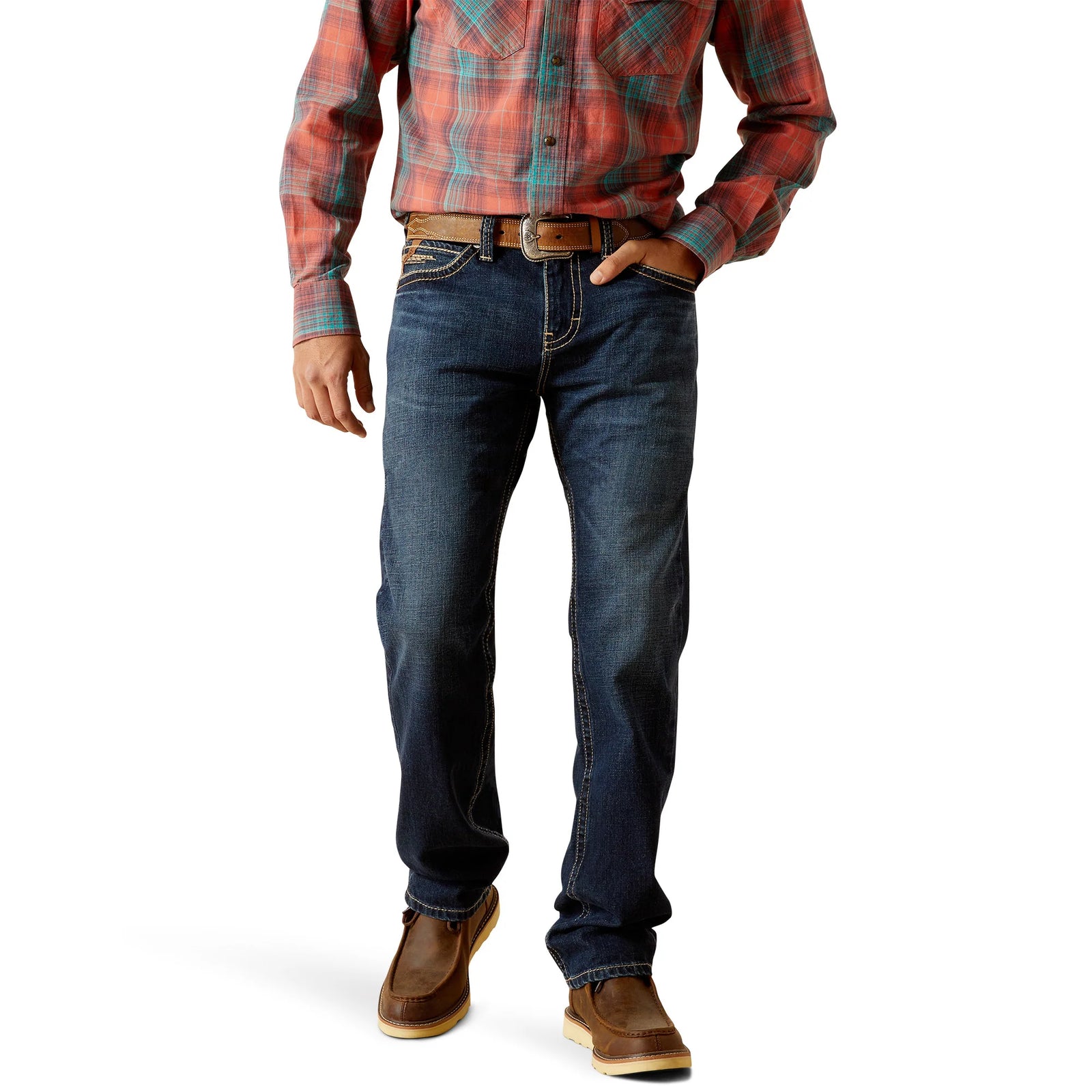 A man standing wearing Ariat Men's M8 Ranger Straight Leg Jeans with a plaid shirt and leather boots.