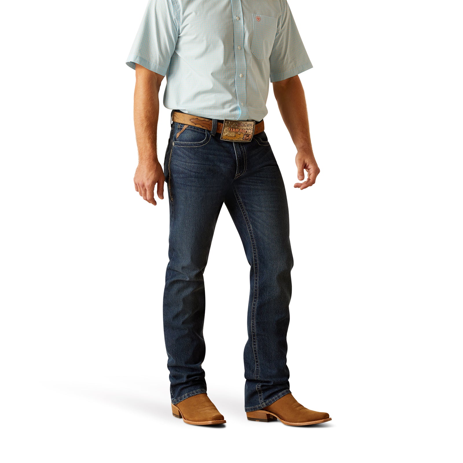 A man standing in a relaxed pose wearing Ariat Men's M4 Ferrin Boot Cut Jean and brown boots.