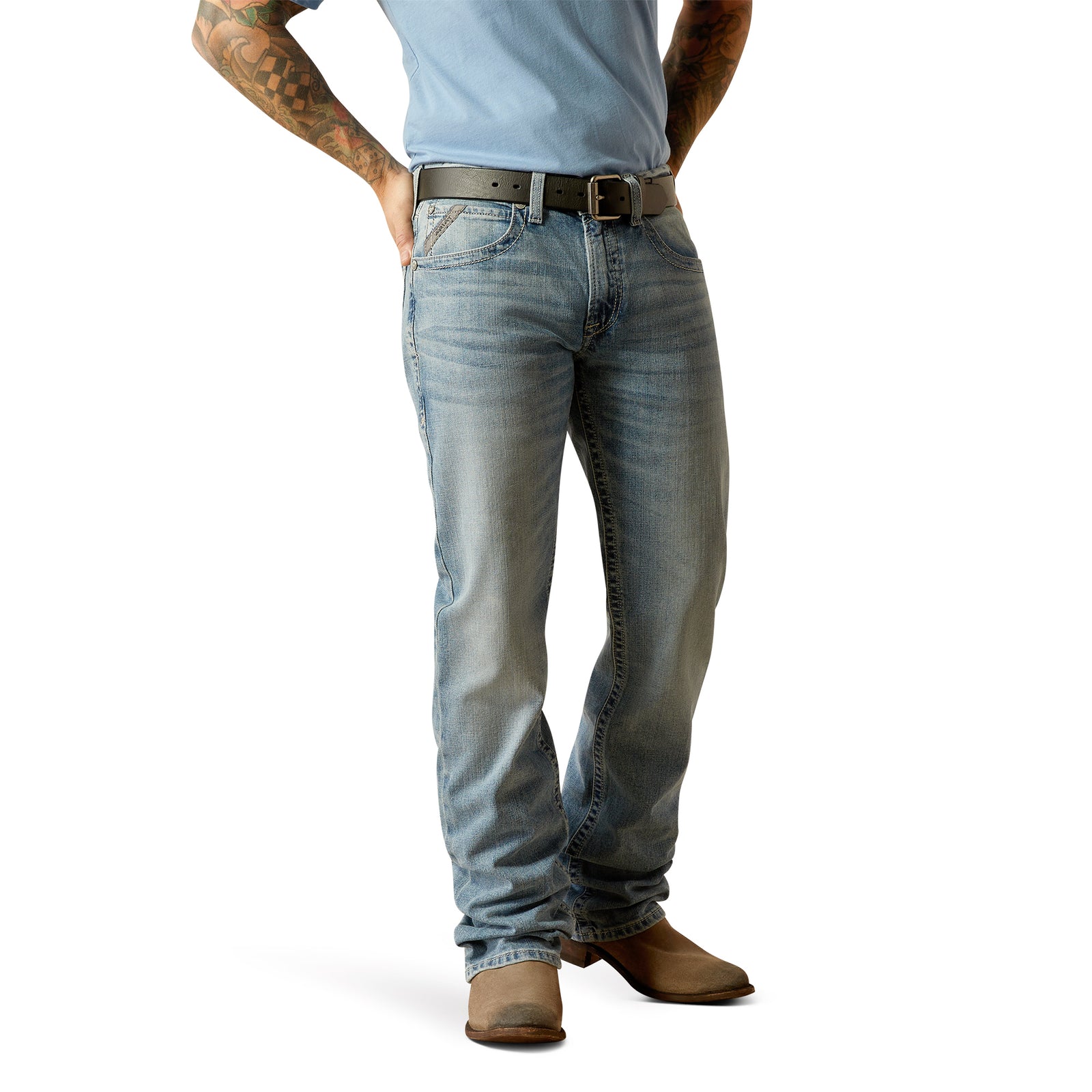 Ariat Men's M4 Apollo Relaxed Fit Jeans. A man standing, wearing Ariat Men's M4 Apollo Relaxed Fit Jeans with a light blue shirt and brown boots.