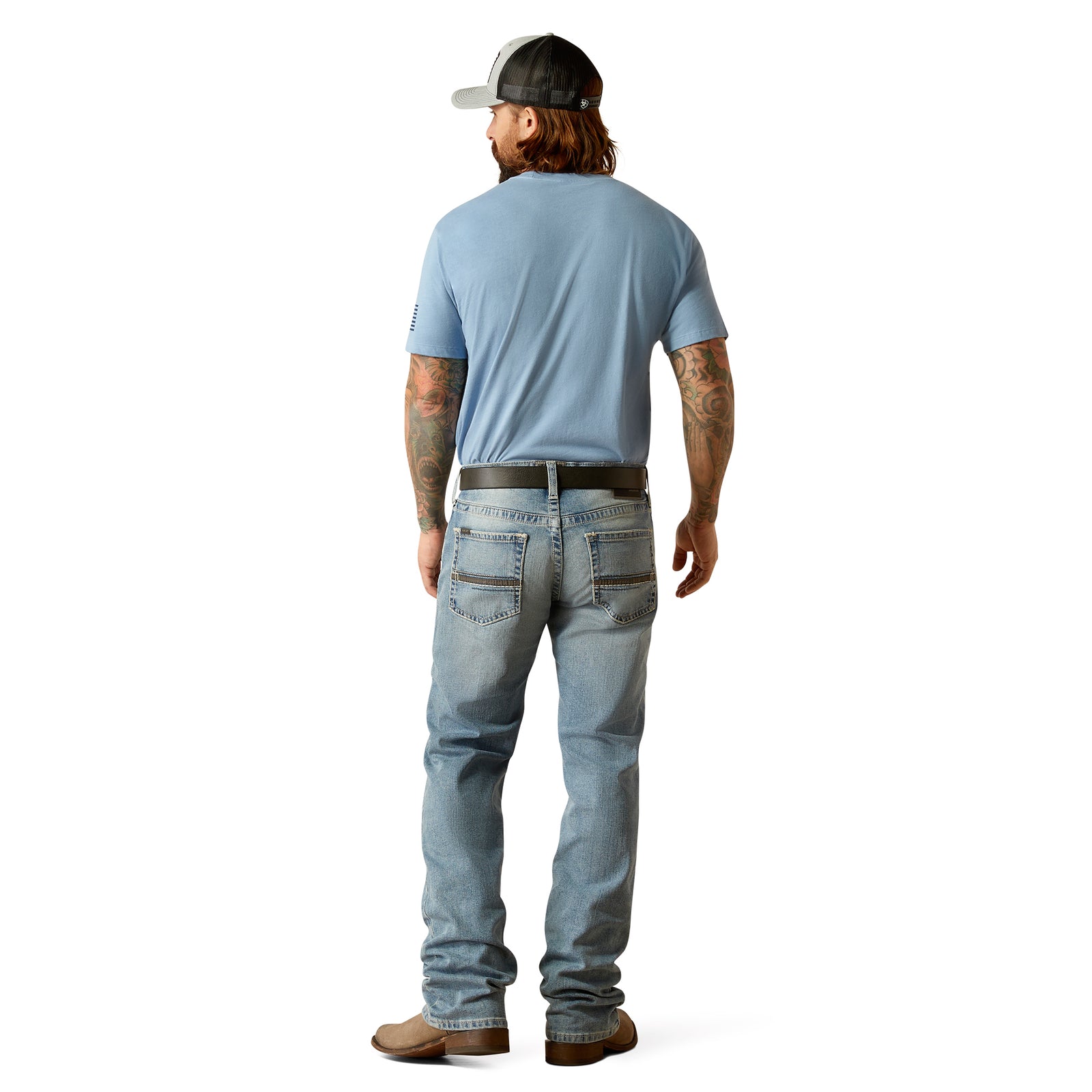 Ariat Men's M4 Apollo Relaxed Fit Jeans. A man standing, wearing Ariat Men's M4 Apollo Relaxed Fit Jeans with a light blue shirt and brown boots.