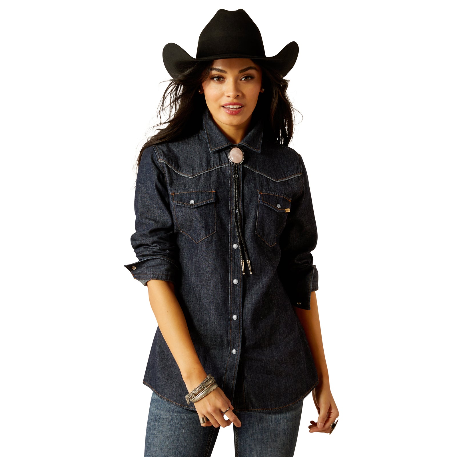 Ariat Women's Farriday Denim  L/S Western Shirt. A woman wearing a dark denim long-sleeved western shirt with a snap front closure and pearl snaps, complemented by a cowboy hat and accessories.