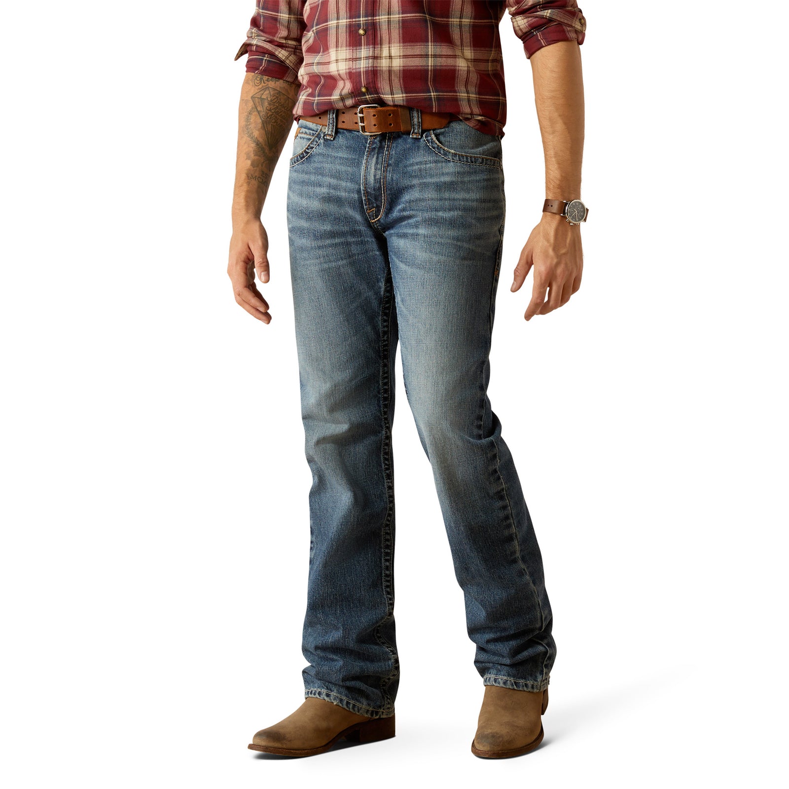 A man standing side-on wearing Ariat Men's M5 Straight Smokey Straight Leg Jean, a checkered shirt, and boots.