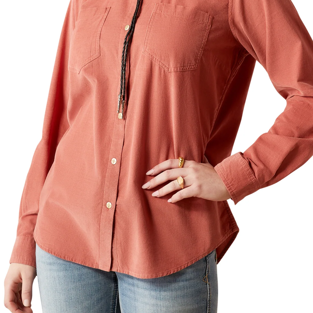 Person wearing a long-sleeve button-up shirt in a warm color with a white background