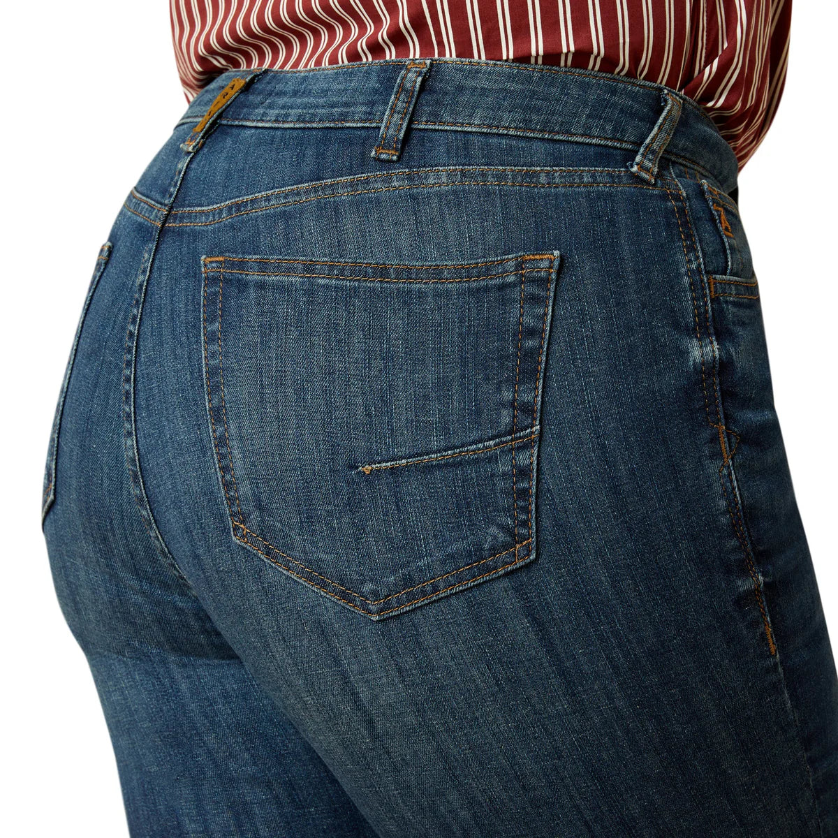 Close-up of blue jeans with a person wearing a red and white striped shirt.