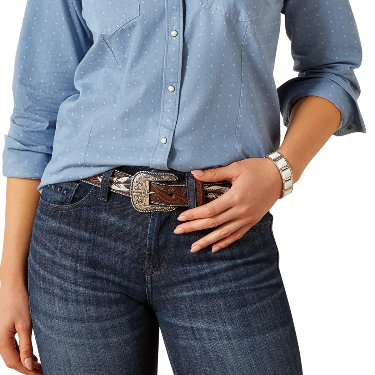 Person wearing a blue patterned shirt and jeans with a decorative belt.