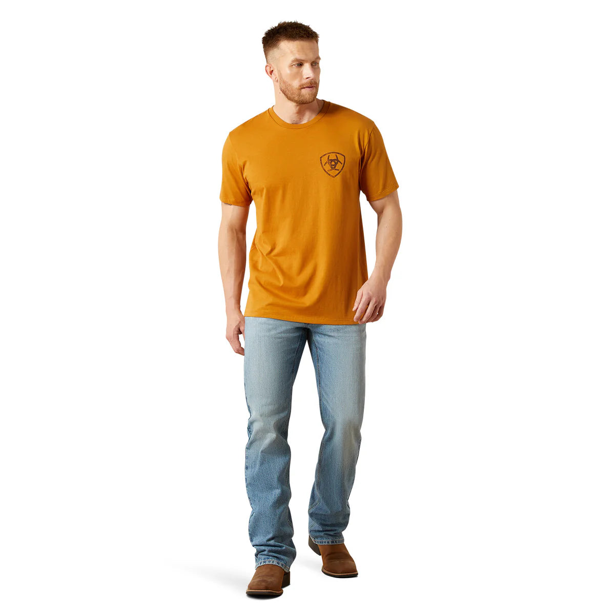 Man wearing a mustard yellow t-shirt with a logo and light blue jeans on a white background