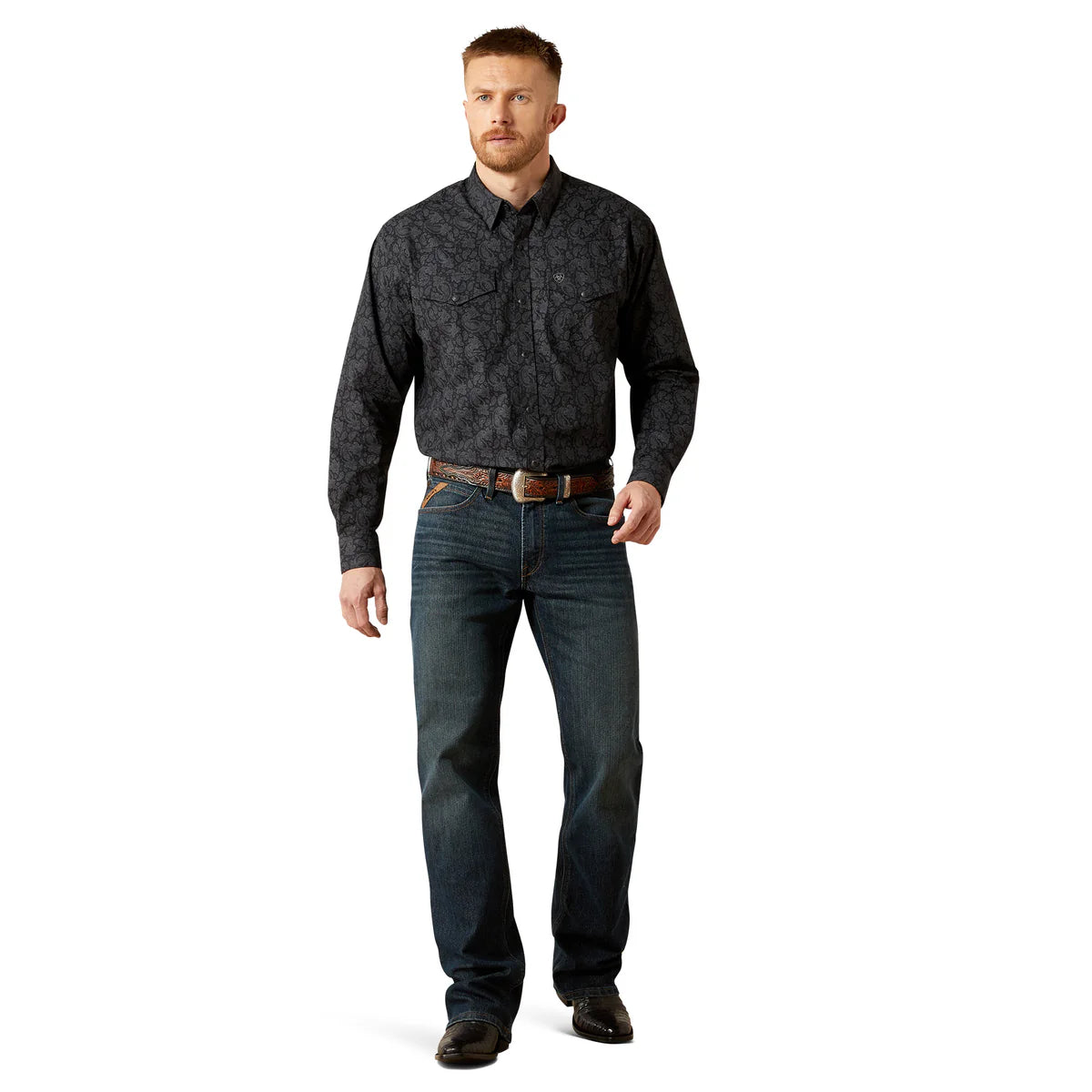 Man wearing a dark patterned shirt and jeans on a white background