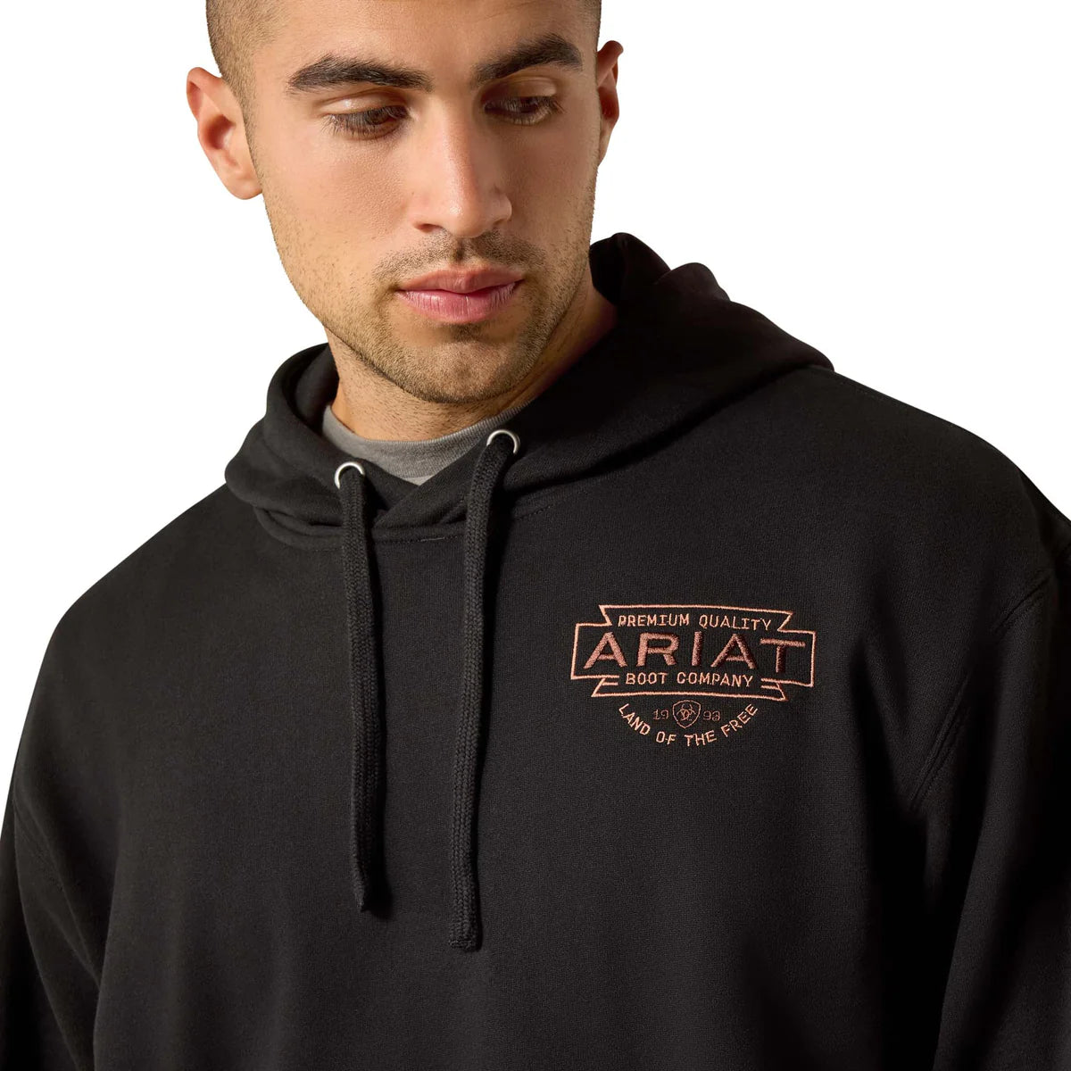 Man wearing a black hoodie with Ariat logo on a white background