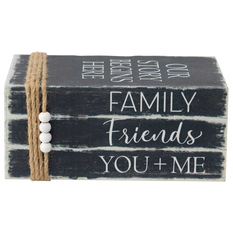 Our Story Begins Here Vintage Books with Beaded Tassel. Stack of black wooden blocks with white text and a rope and beads decoration on a white background