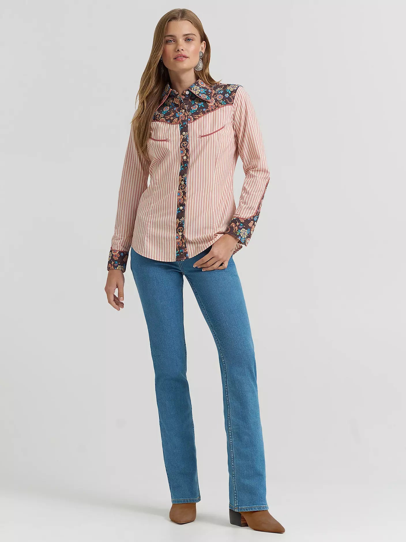 Woman wearing a pink checkered shirt with floral accents and blue jeans on a white background