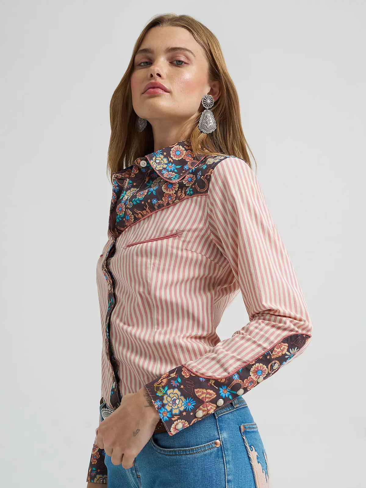Woman wearing a pink striped shirt with floral embroidery on a white background