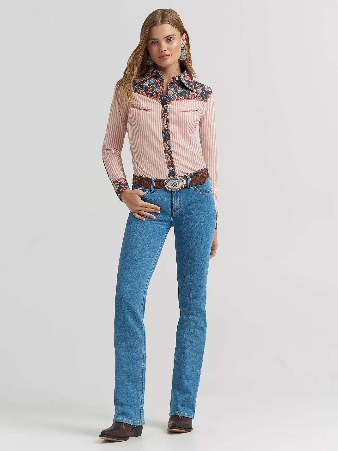 Woman wearing a cowboy hat and blue jeans with a decorative back pocket in a room with brown leather furniture.