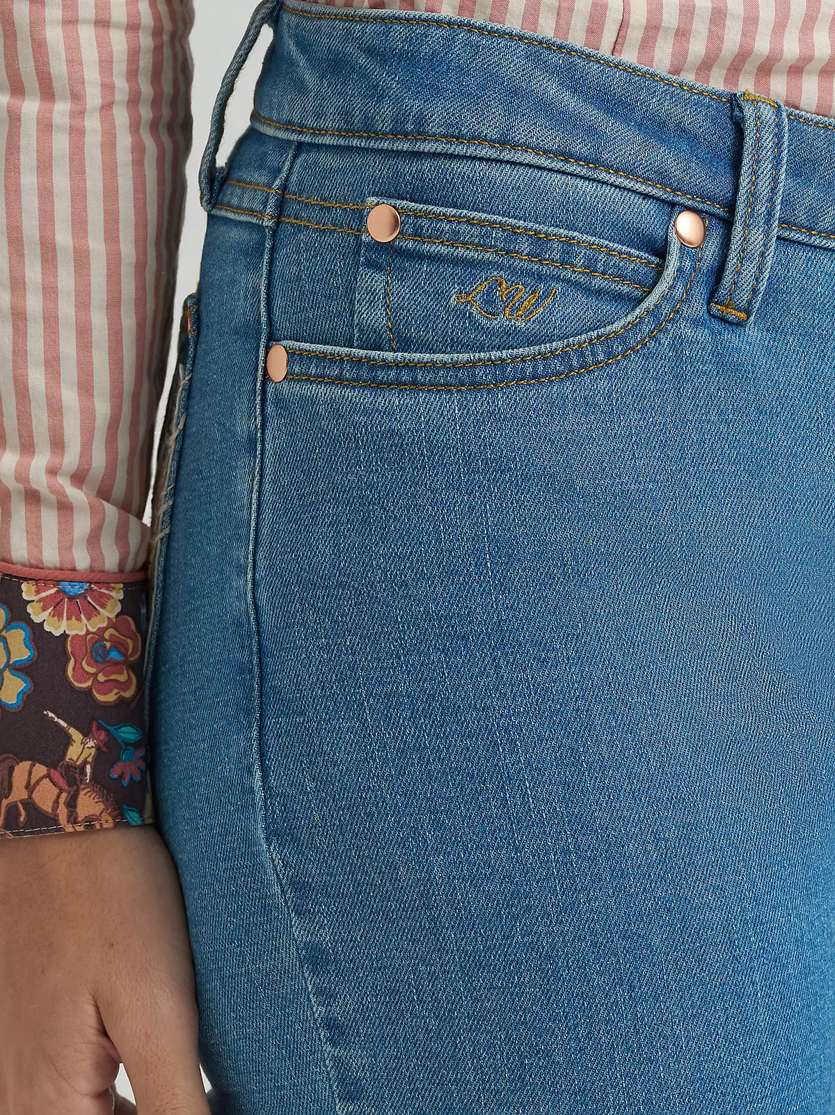 Close-up of blue jeans with a brand logo on the pocket, worn by a person.