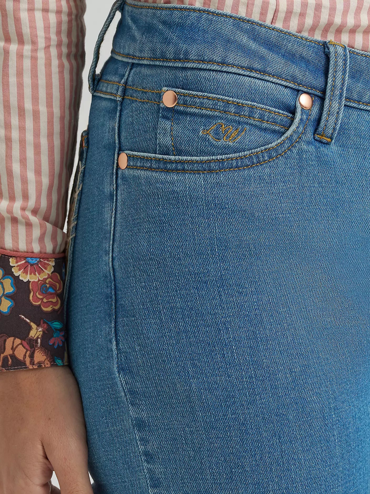 Close-up of blue jeans with a brand logo on the pocket, worn by a person.