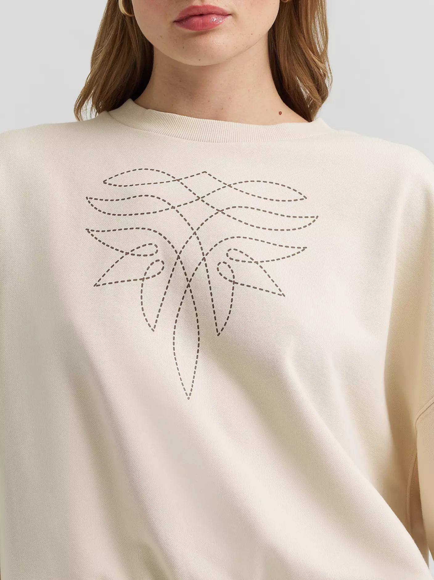 Beige sweater with a decorative leaf pattern on a plain background