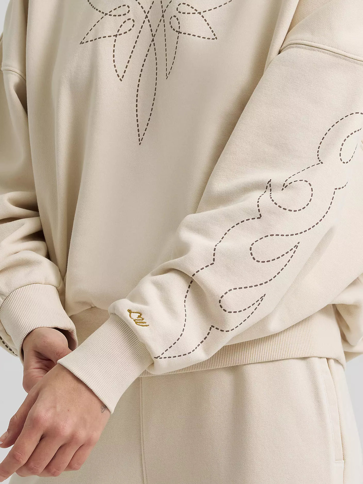 Beige outfit with embroidered designs on a plain background