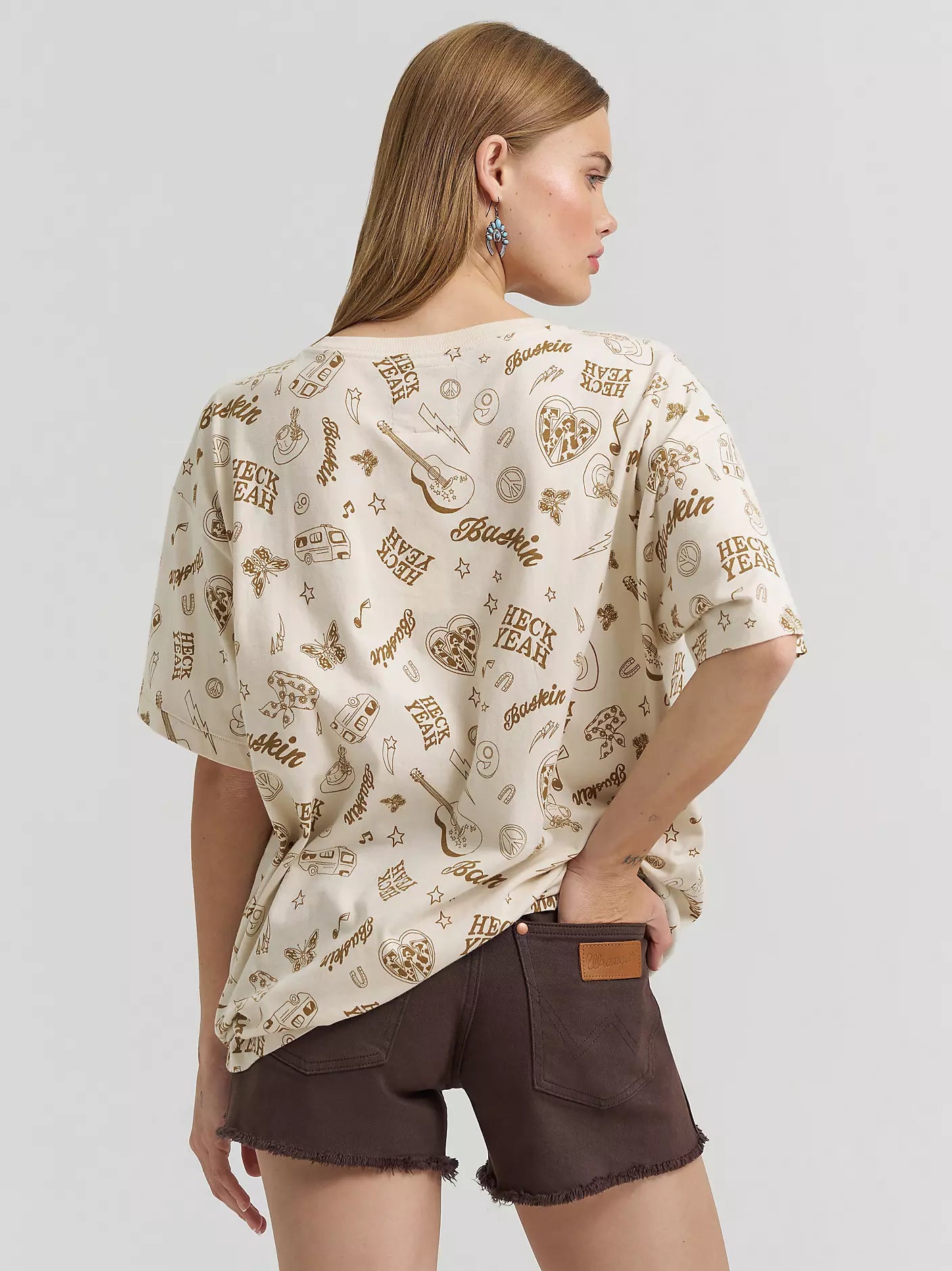 Woman wearing a patterned beige top and brown shorts on a white background