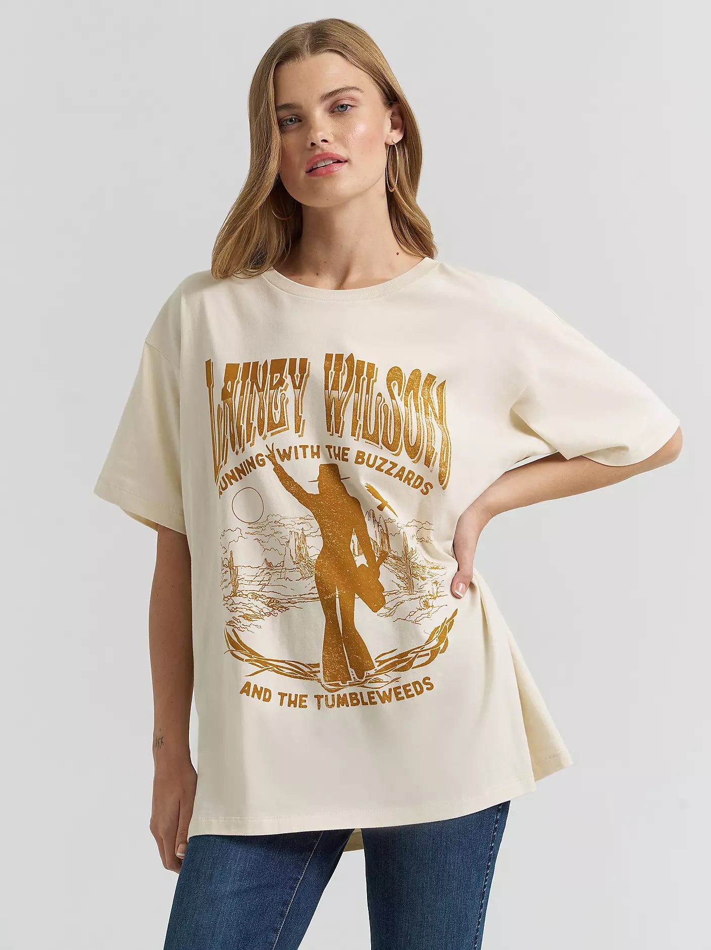 Woman wearing a graphic t-shirt and jeans leaning on a vintage truck.