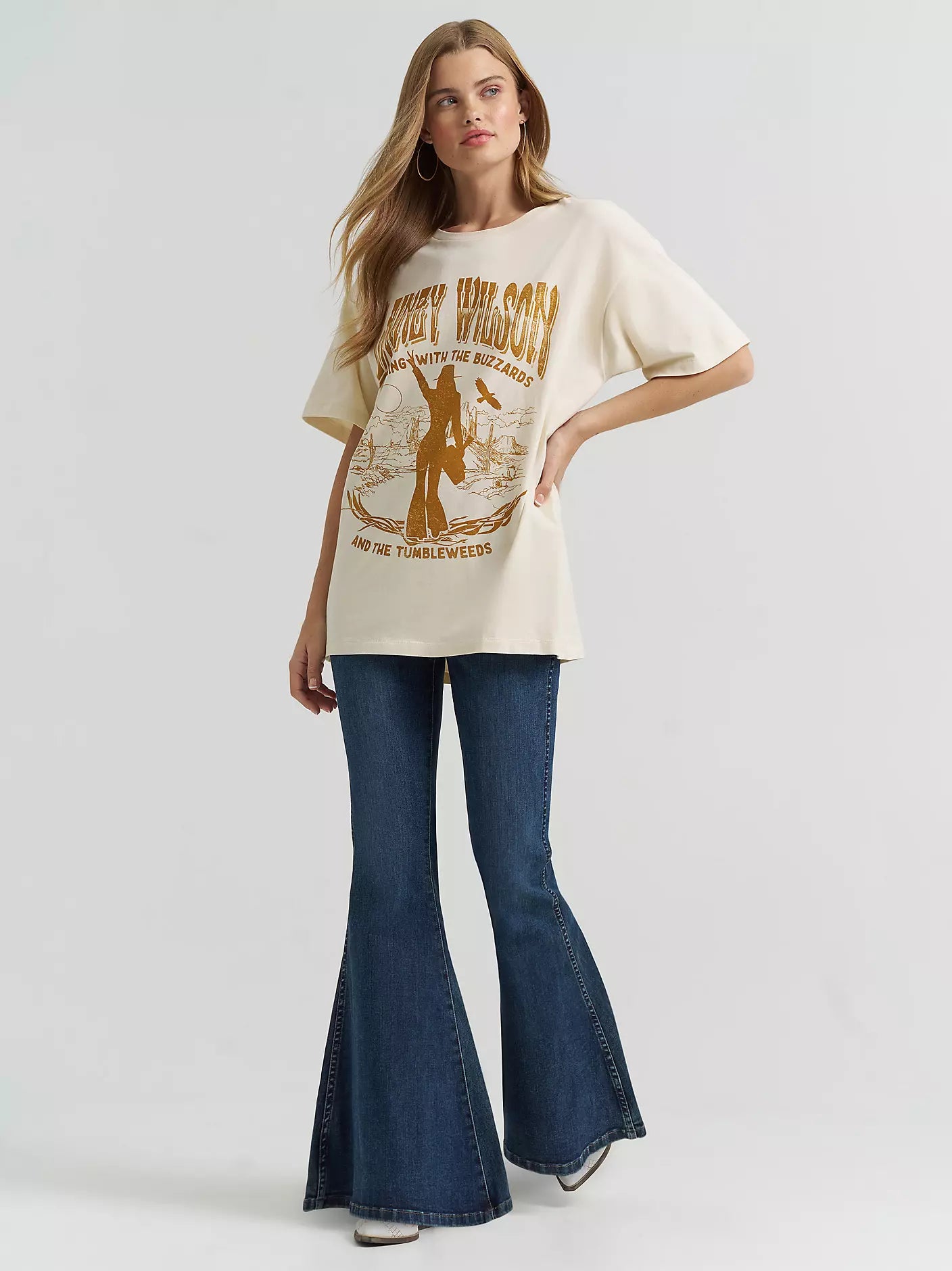 Woman wearing a graphic t-shirt and blue flared jeans on a white background
