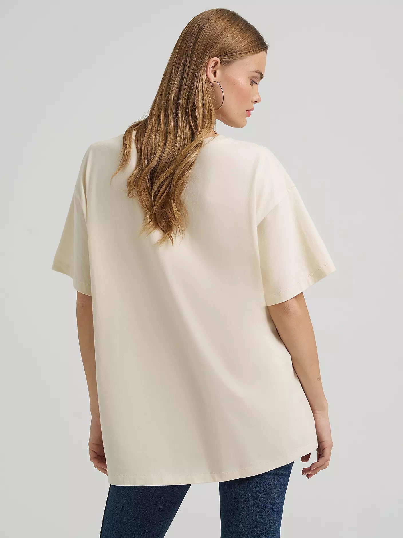 Woman wearing a beige oversized t-shirt on a plain background