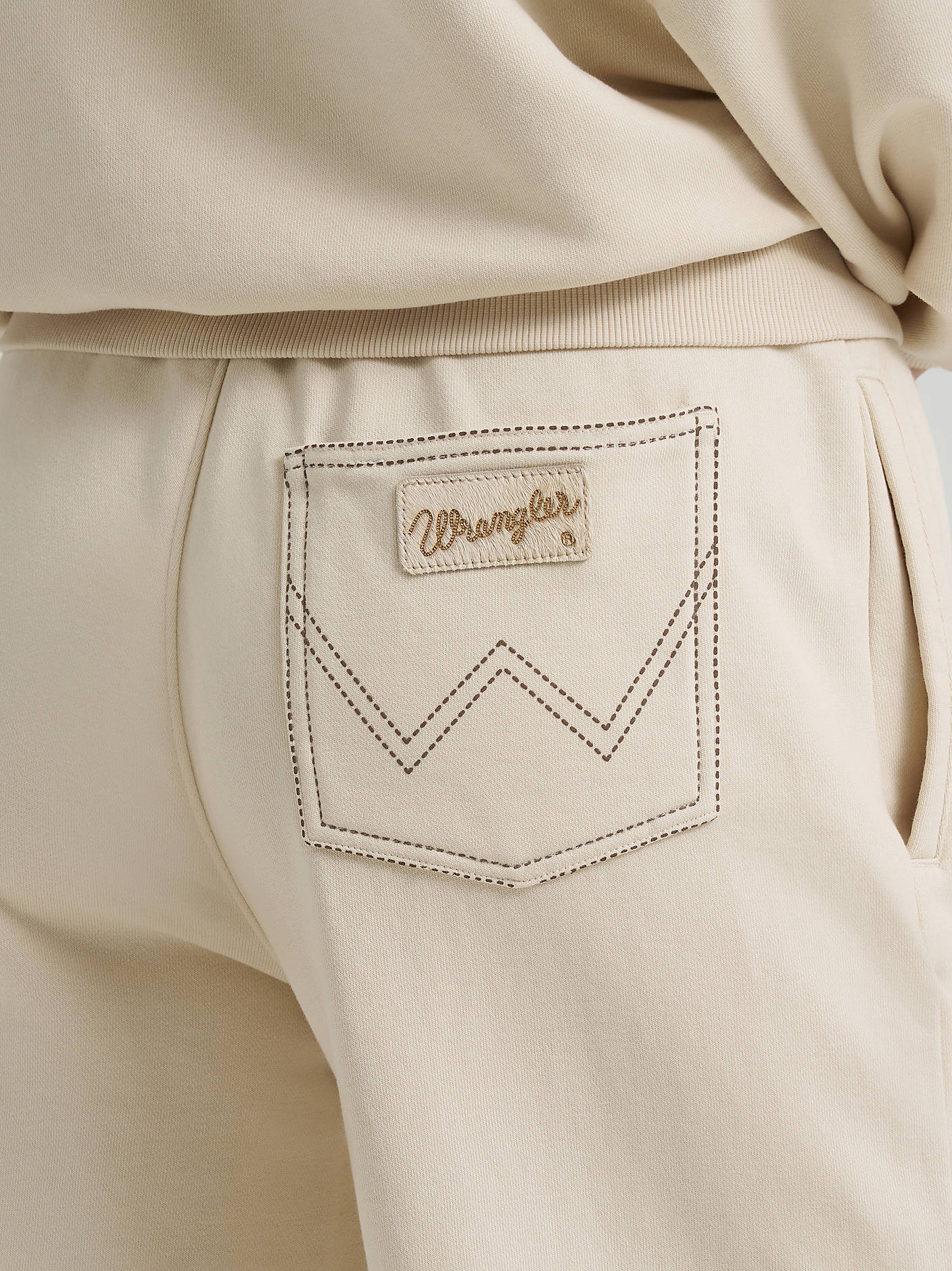 Beige pants with a Wrangler logo on the pocket