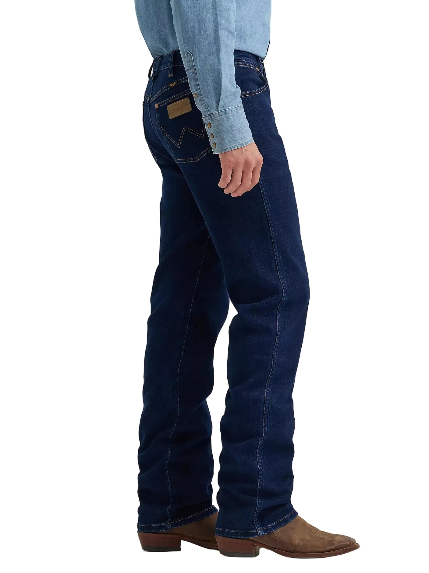 A side profile view of a person wearing dark blue denim jeans, a light blue denim shirt, and brown leather cowboy boots, set against a plain light gray studio background.