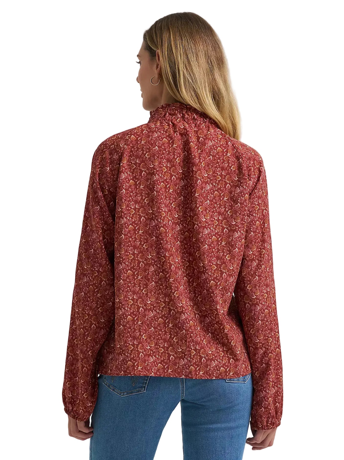Woman wearing a red floral blouse and blue jeans on a gray background