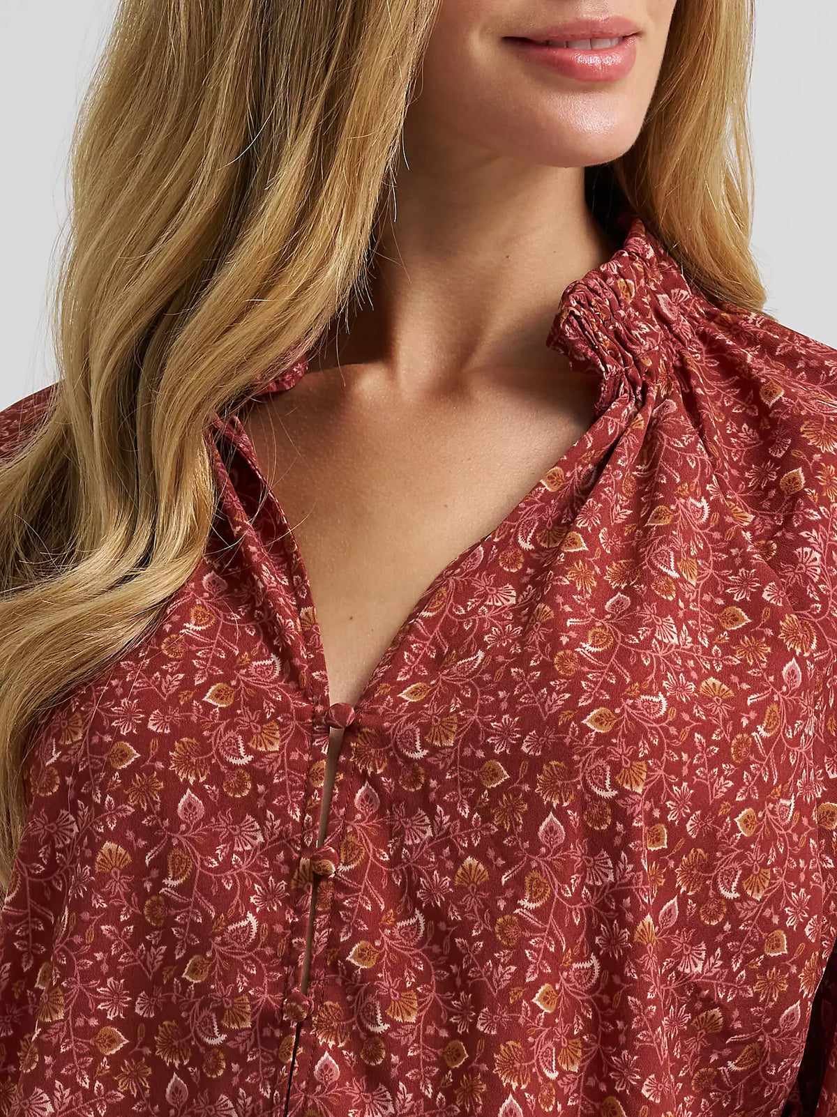 Close-up of a woman wearing a red floral blouse against a white background