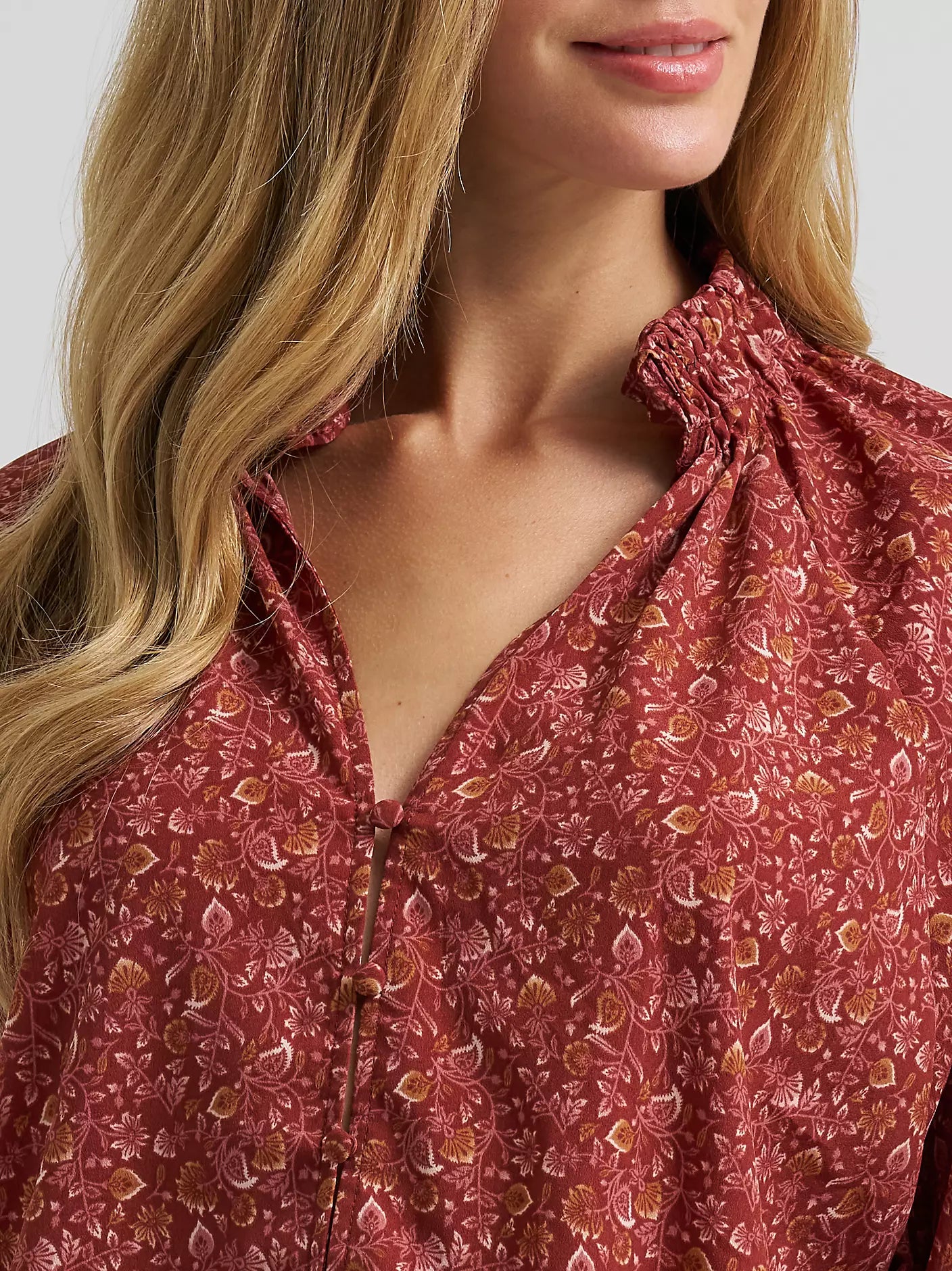 Close-up of a woman wearing a red floral blouse against a white background