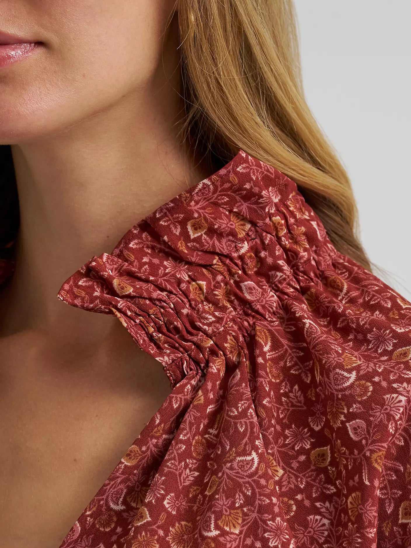 Close-up of a person wearing a red floral patterned top with a blurred background