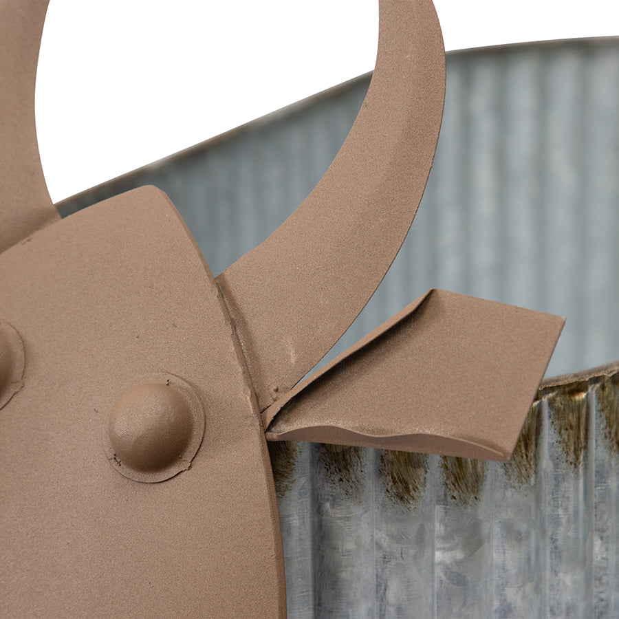 Nested Cow Planters Set of 2. Close-up of a brown metal tool against a corrugated metal background