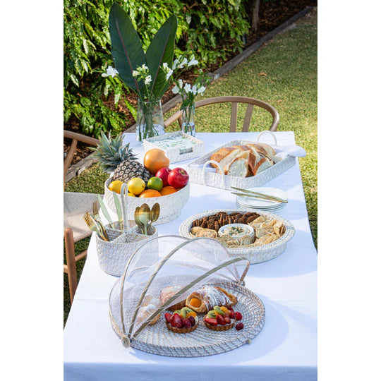 Whitehaven Woven Utensil Caddy Holder. Outdoor table setting with food and flowers on a white tablecloth