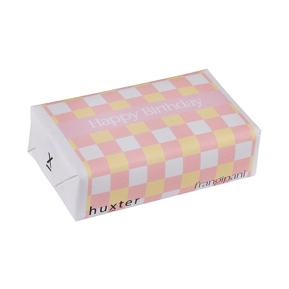 Huxter Happy Birthday Soap. A packaged bar of Huxter soap with a Happy Birthday greeting on the wrapping, featuring a pink and yellow checkered pattern.