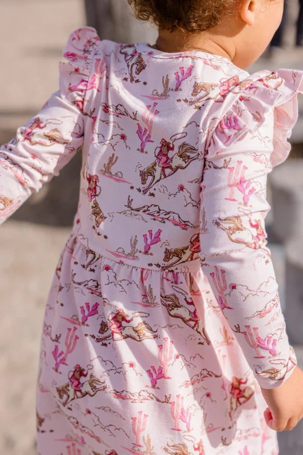 Young girl in a floral dress standing on wooden posts with a clear sky background