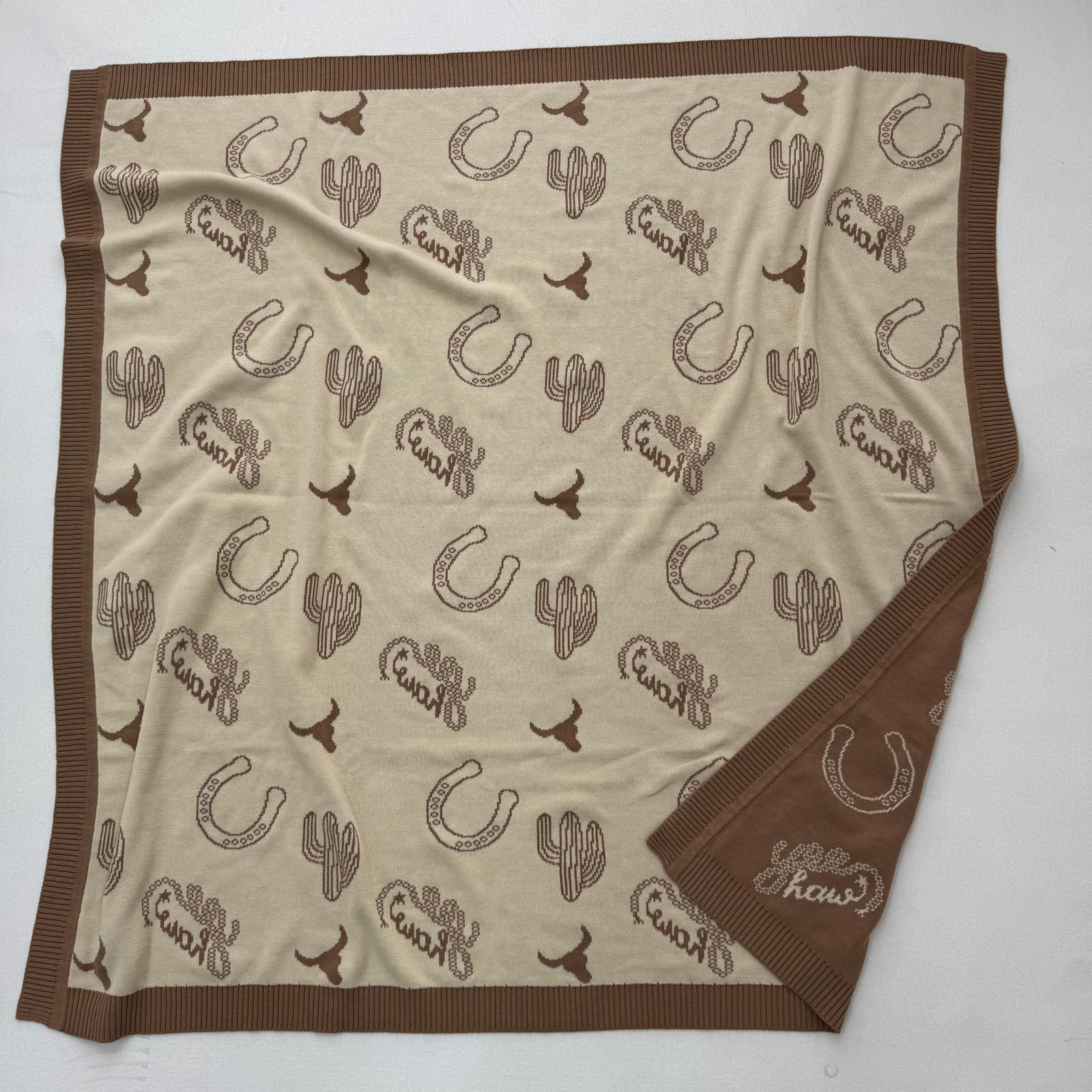 Blanket with cowboy-themed patterns on a white background