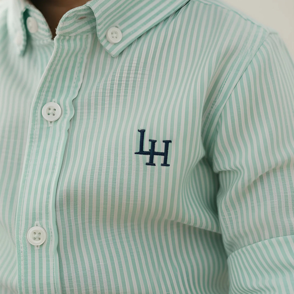 Green and white striped shirt with a logo on a child, close-up view.