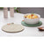 Nash Green Set of 2 Trivets. Bowl of spaghetti on a green coaster with a woven trivet on a white surface.
